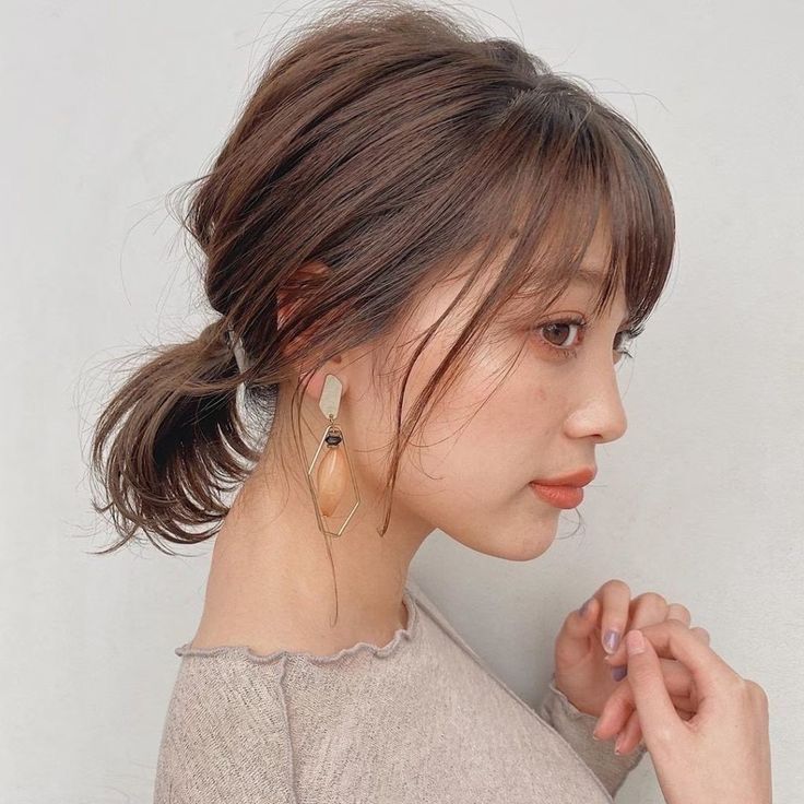 A side profile of a woman with short ponytail and bangs.