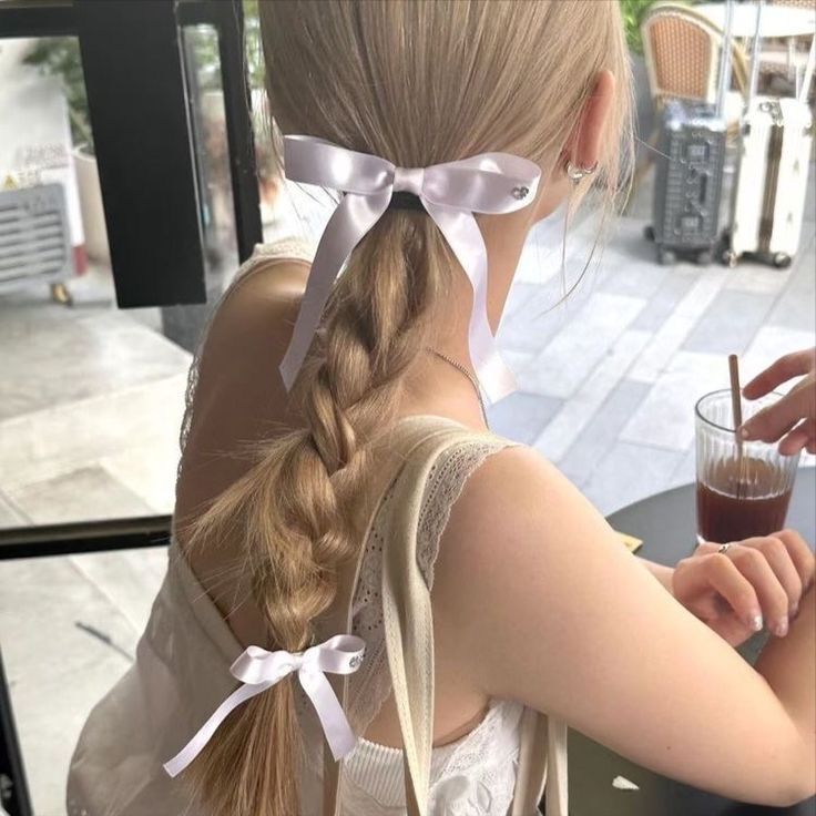 A portrait of woman with blonde braid and white bows.