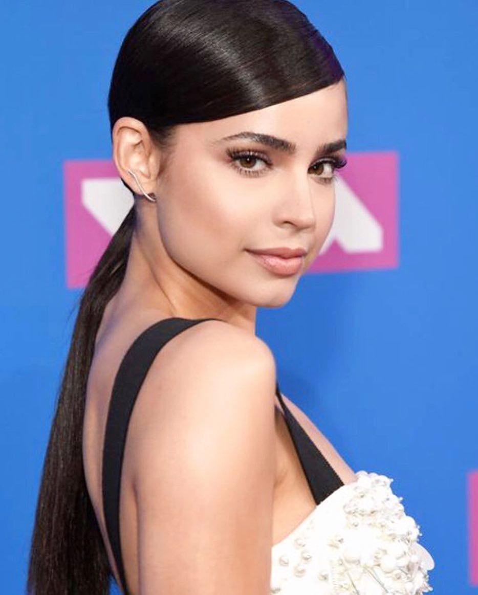 A portrait of Sofia Carson with side-parted ponytail.
