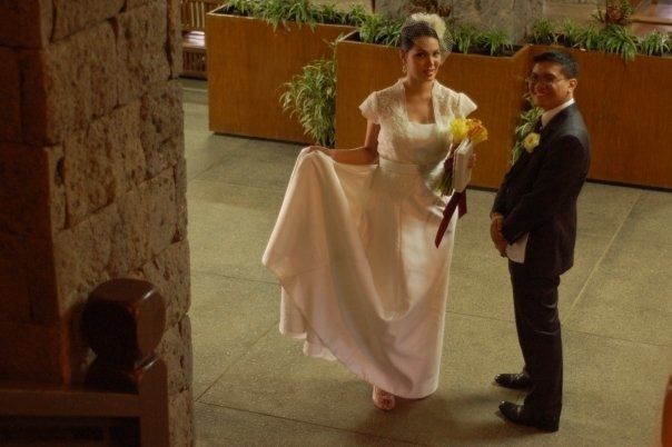 Young married couple, woman holding wedding dress with man in suit. 