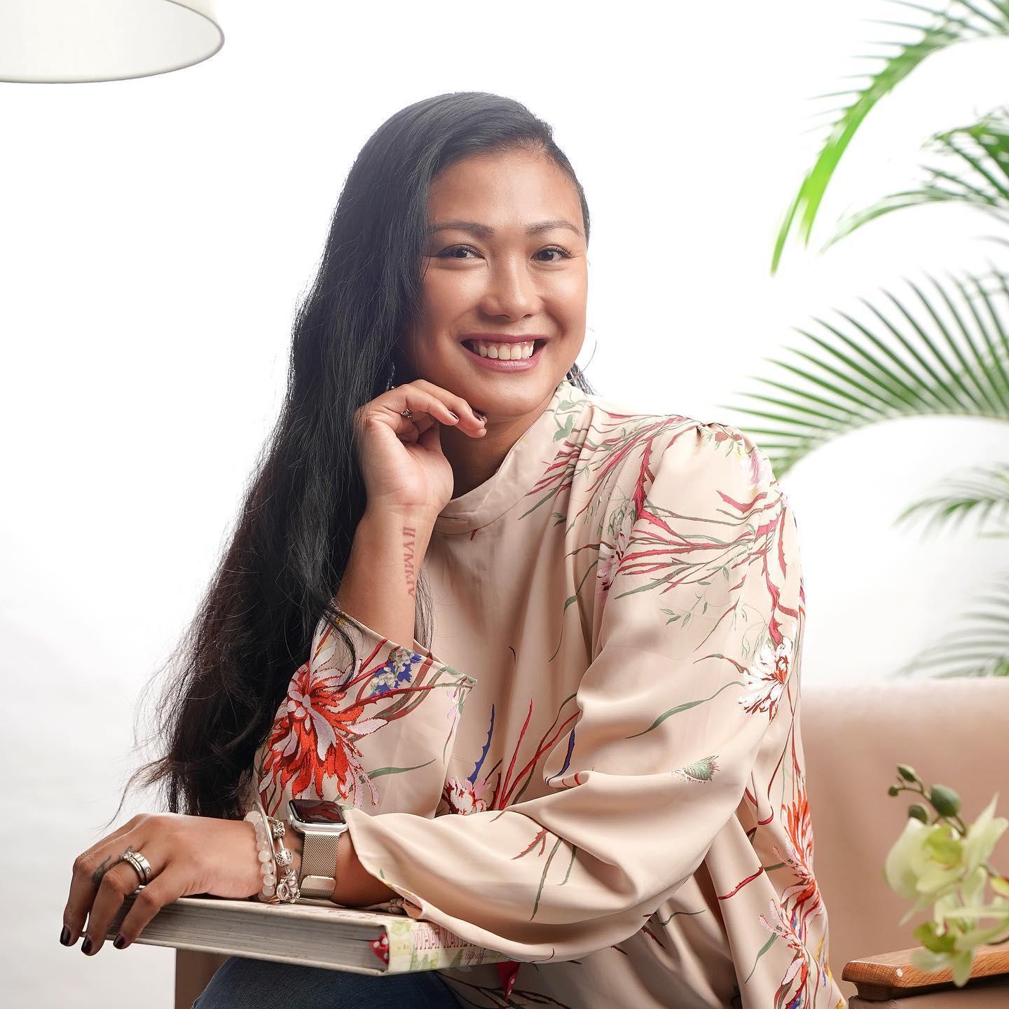 Smiling Asian woman in a pink, floral shirt 