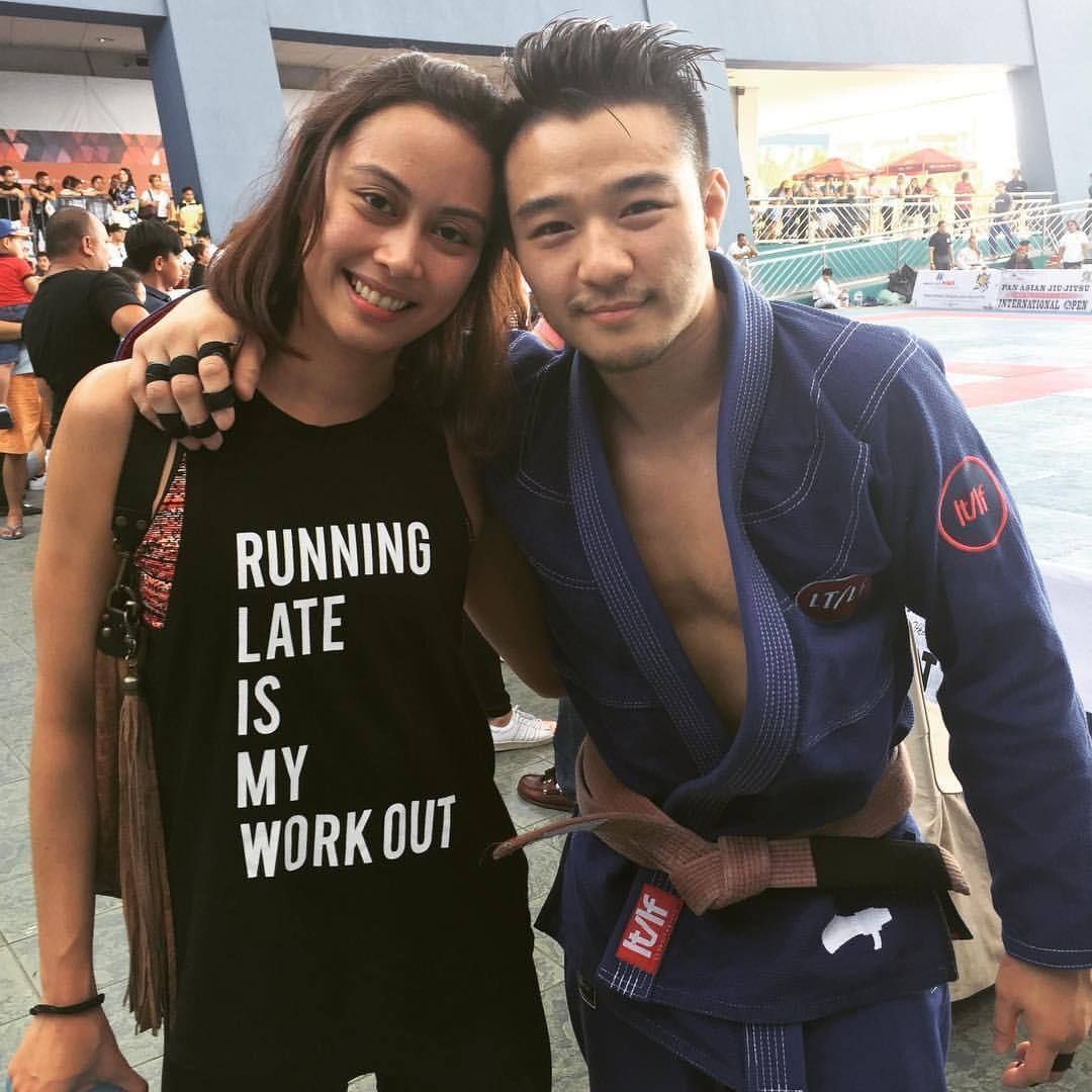 Asian couple in athletic gear, man in Brazilian Jiujitsu gi at a sporting event. 