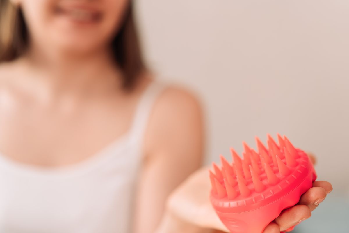 Woman holding a silicone scalp brush.