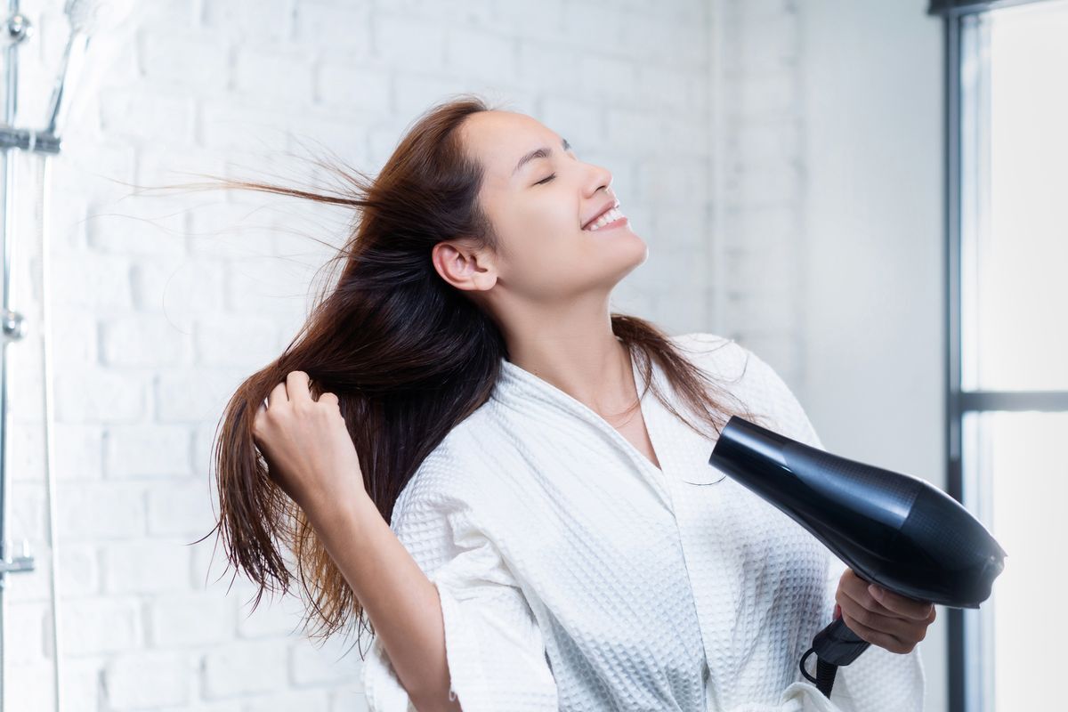 Woman drying her hair with a blow dryer.