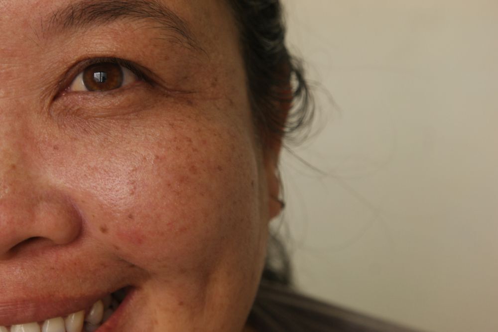 Tanned Asian woman with crow's feet.