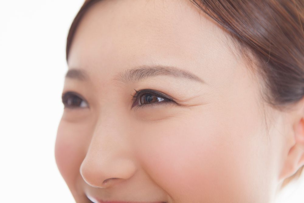 Asian woman smiling with crow's feet.