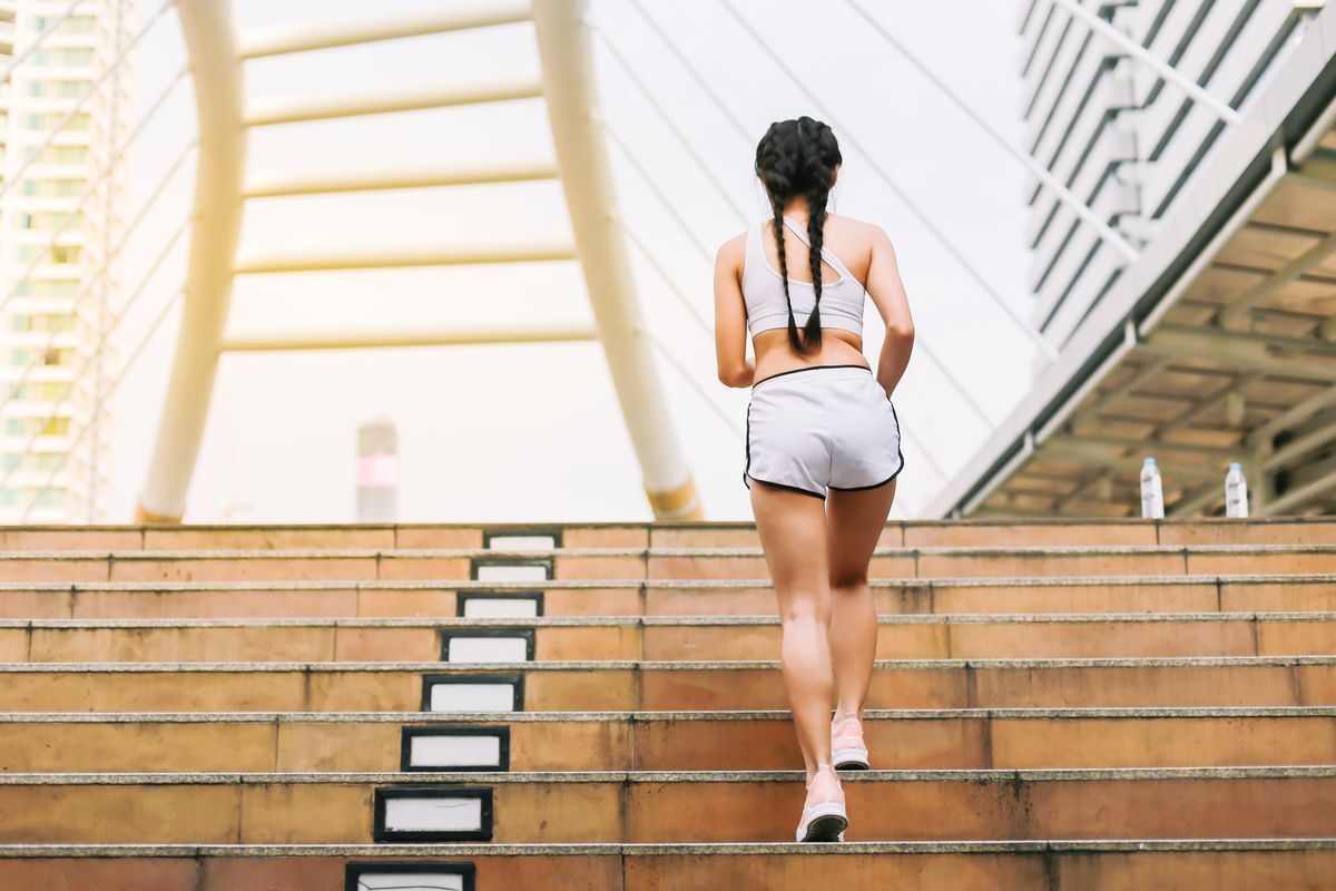 Asian woman wearing shorts running up the stairs. 