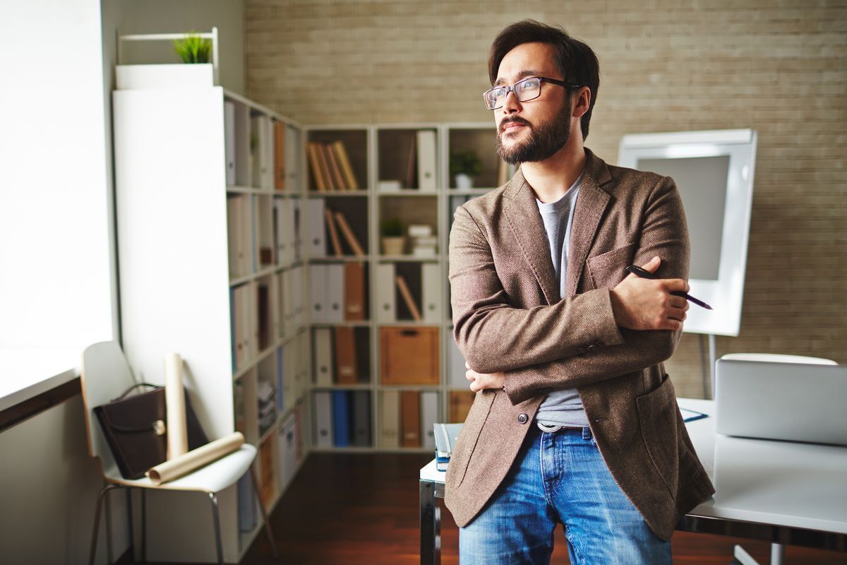 Asian businessman looking away with hands folded in the office