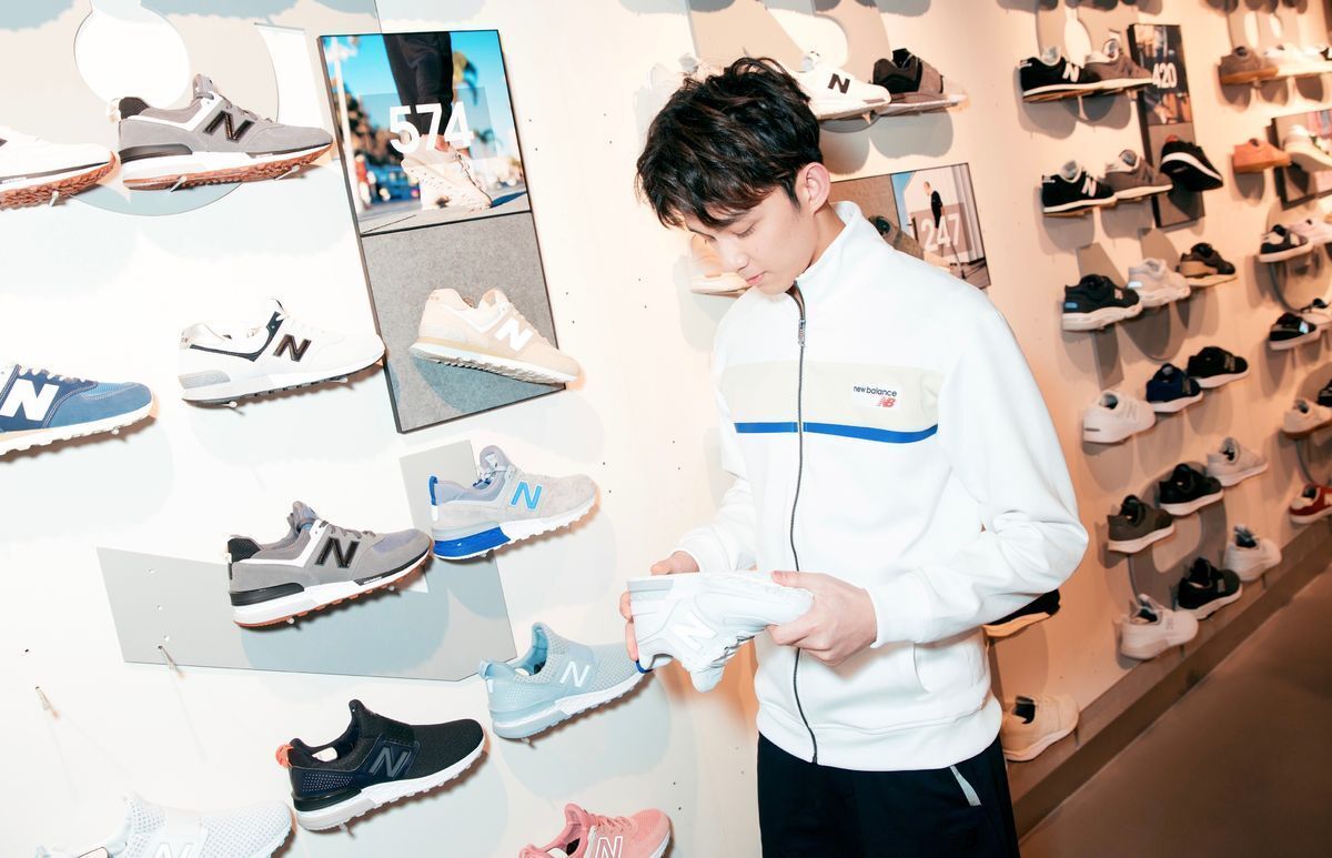 Young Asian man at a sneaker shop looking at a sneaker.