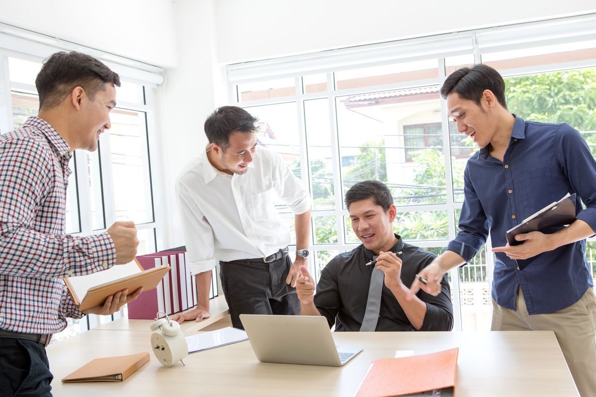 Filipino man in office cheering with officemates