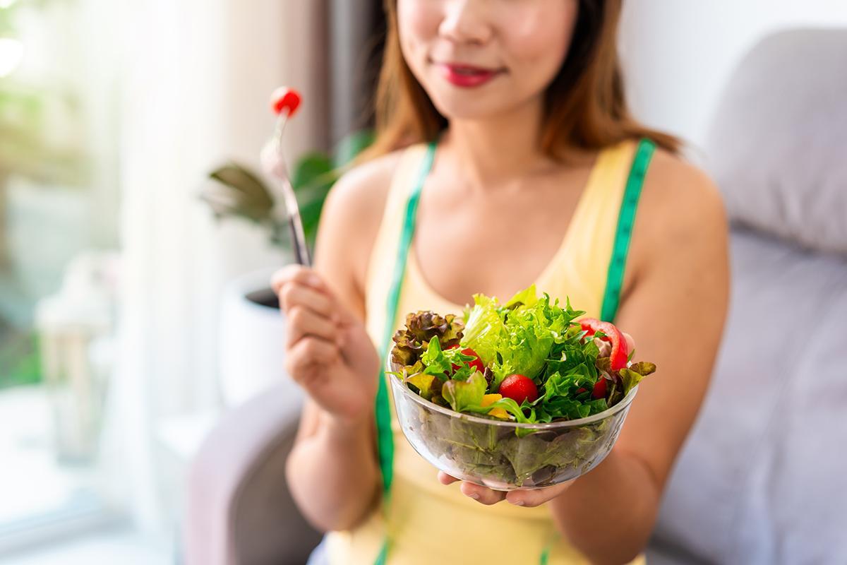 Woman holding a clear bowl of green lettuce