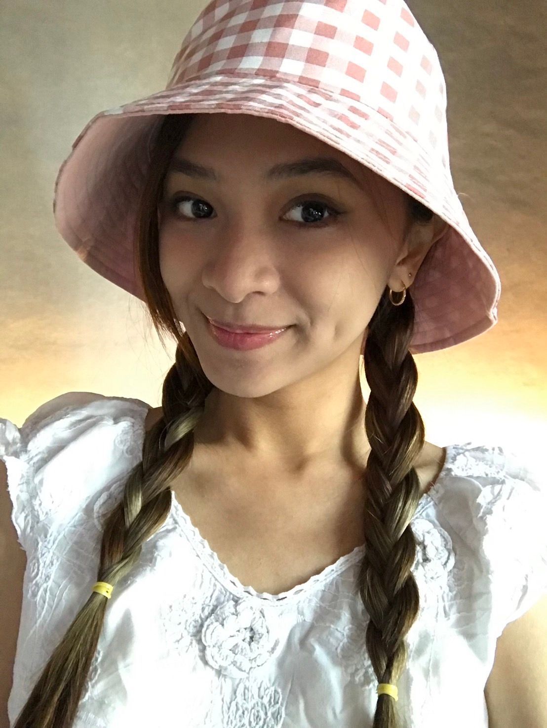 A portrait of woman with braided pigtails and bucket hat.