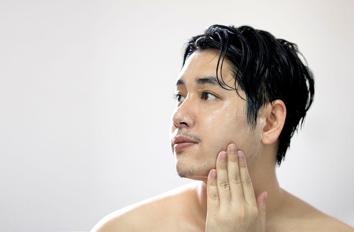 Asian man rubbing face with soap