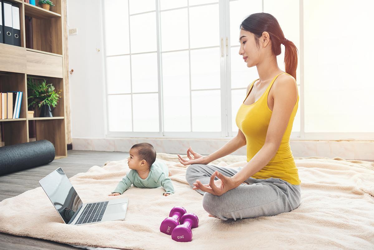 Asian mom doing yoga with baby on floor