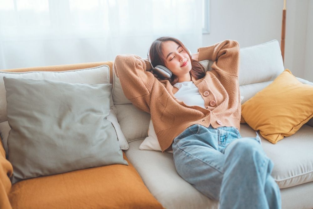Woman relaxing on a sofa with headphones on.