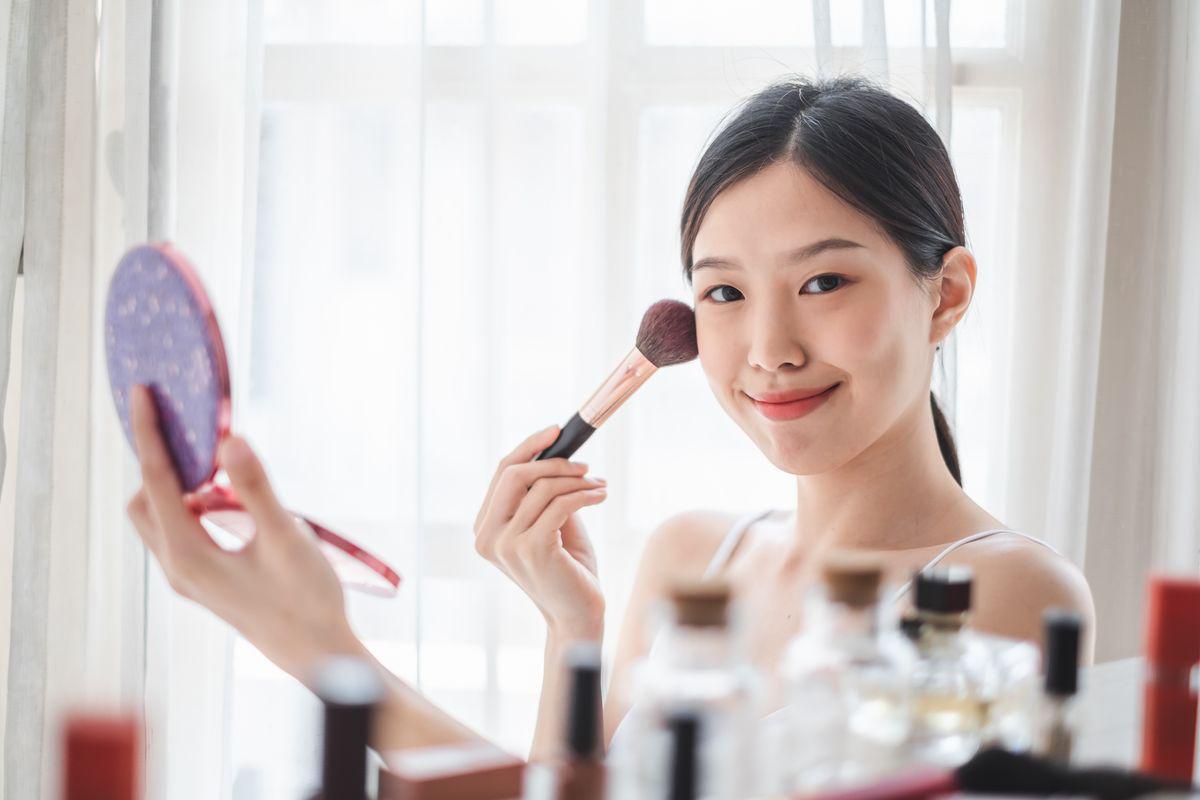 Asian woman applying makeup