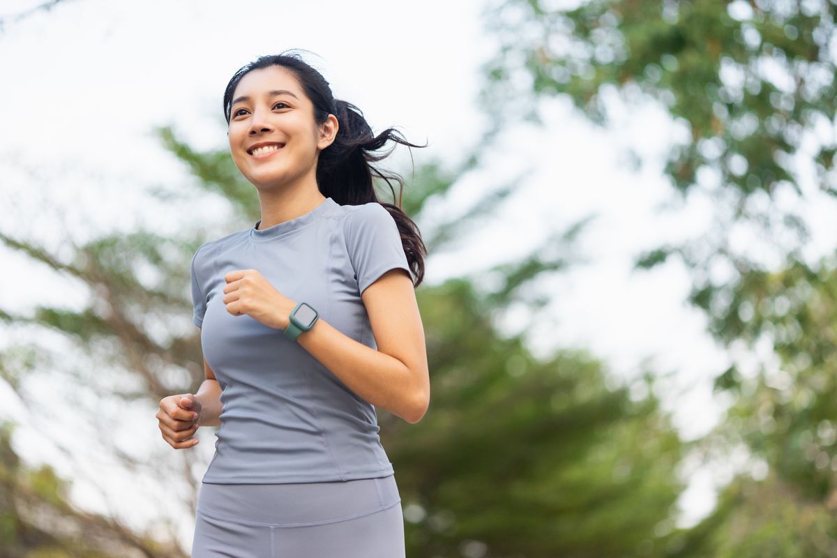 Asian woman running while smiling in the morning.