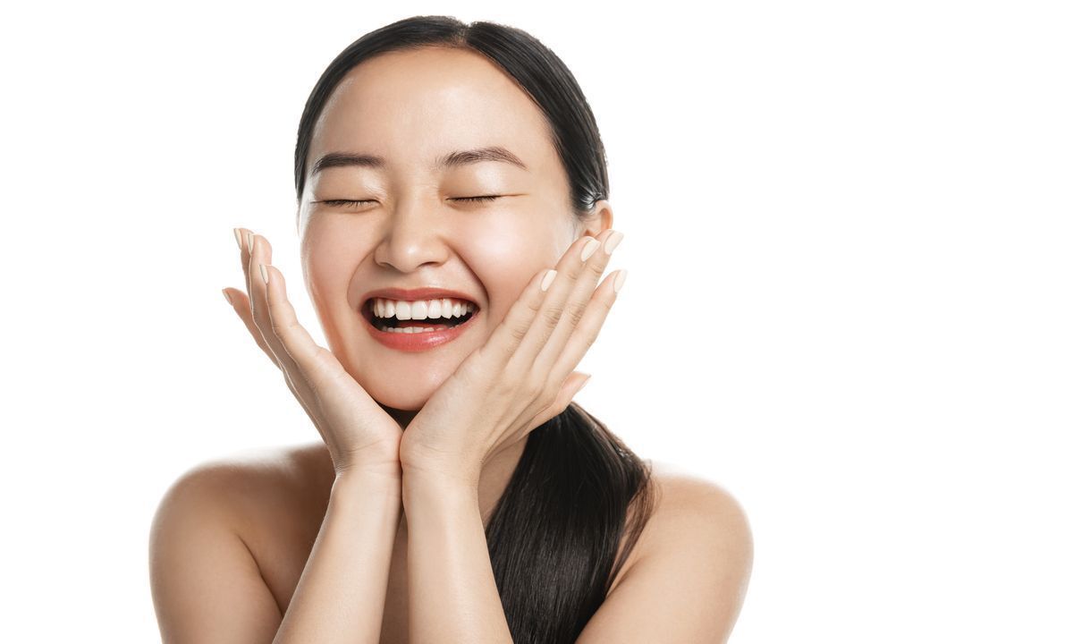 Asian woman laughing while cupping her face