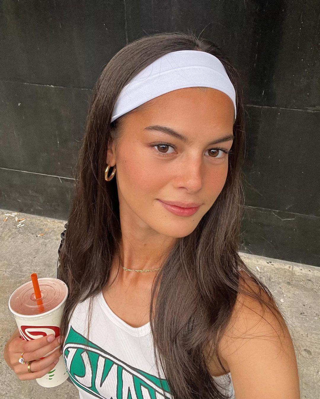A portrait Bethany Talbot with white headband holding a cup of drink.