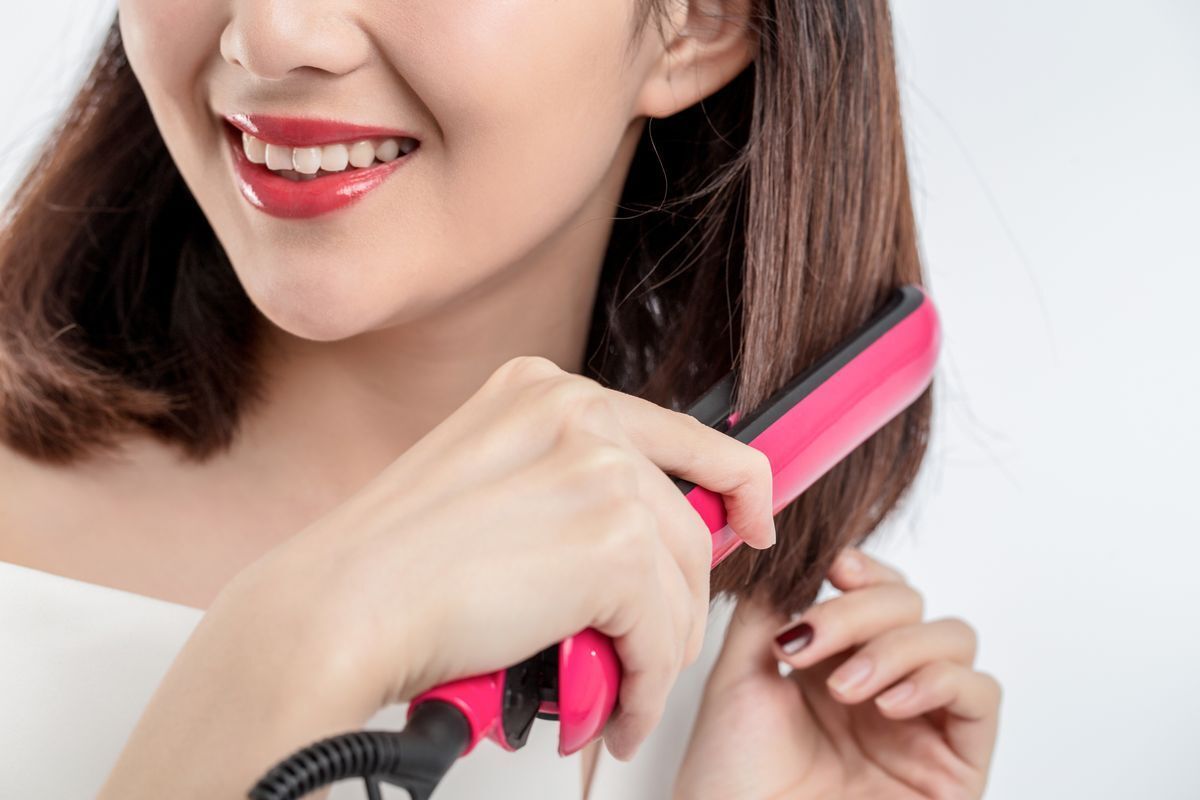 Asian woman straightening her hair