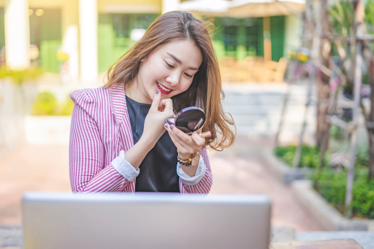 Asian woman retouching her makeup 