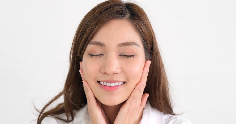 Asian woman holding face 