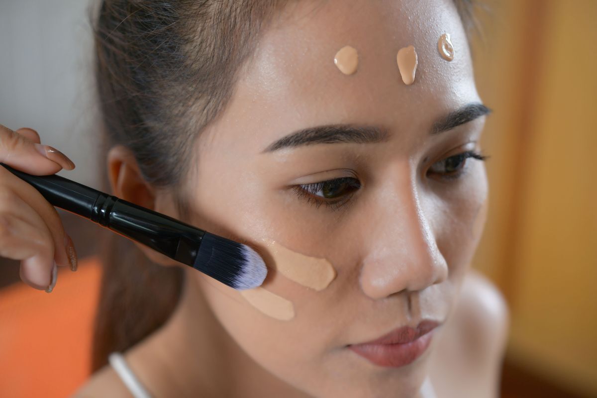 Asian woman with foundation on her face, getting her makeup done. 