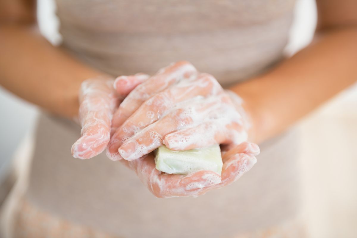 Closeup of hands covered in soap, holding a soap bar.