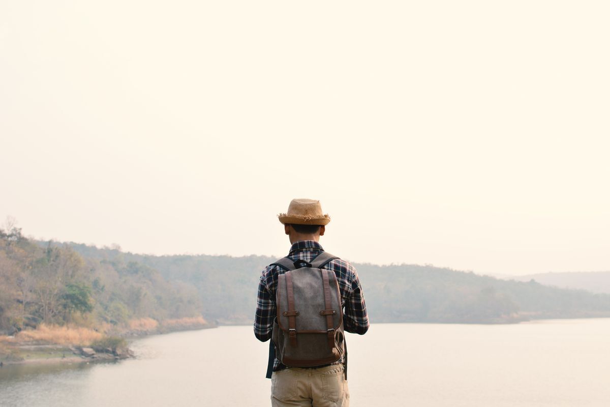Back of an Asian man looking into the distance with a lake in the background.