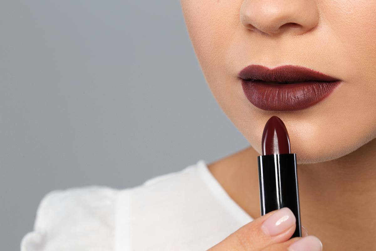 Woman applying dark lipstick