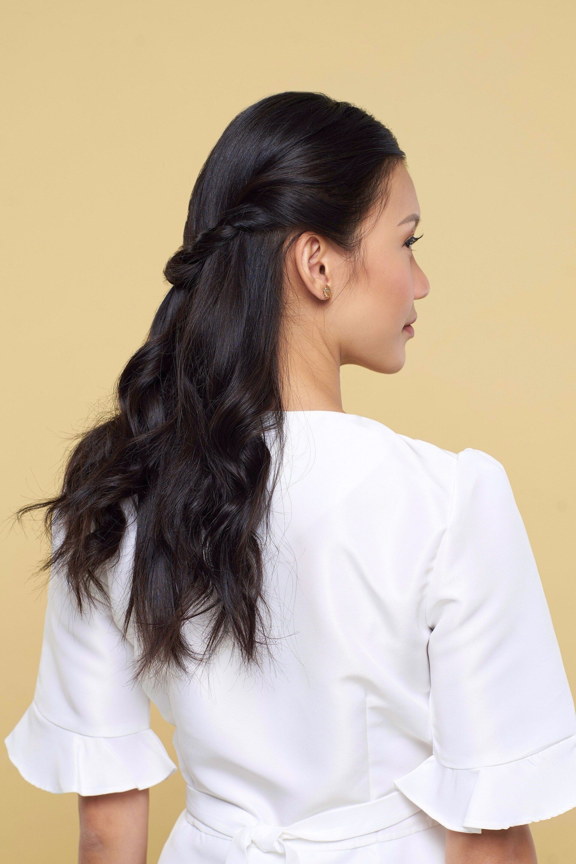 Back view of an Asian woman with wavy hair in a half ponytail.