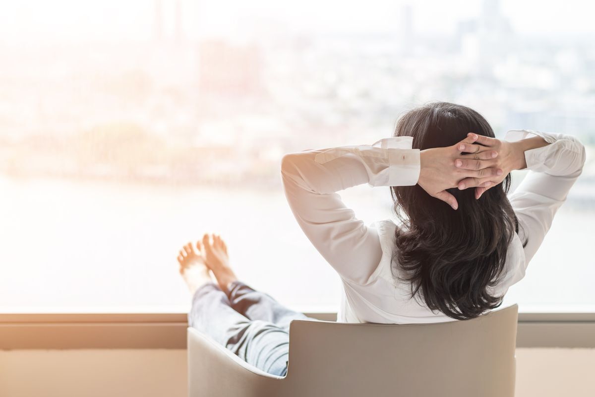 A woman trying to relax by looking out at the view with her feet up and arms behind her head.