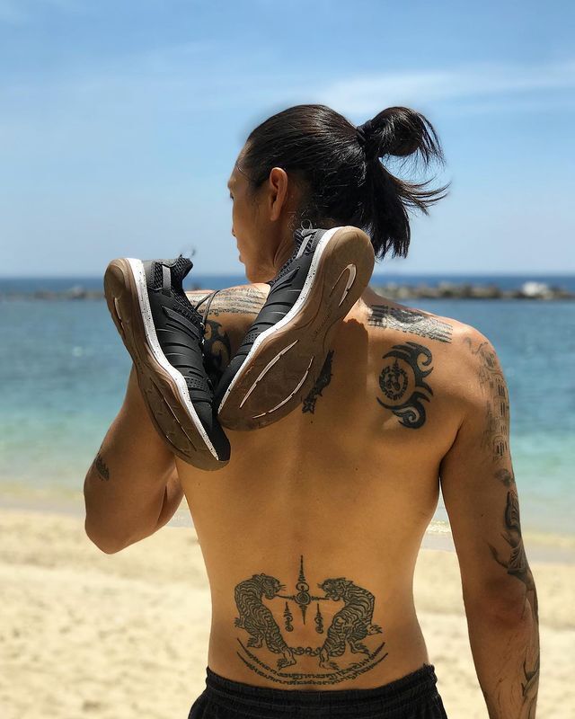 A portrait of Sky Yang’s back with a man bun and a pair of black sneakers dangling on his shoulders.