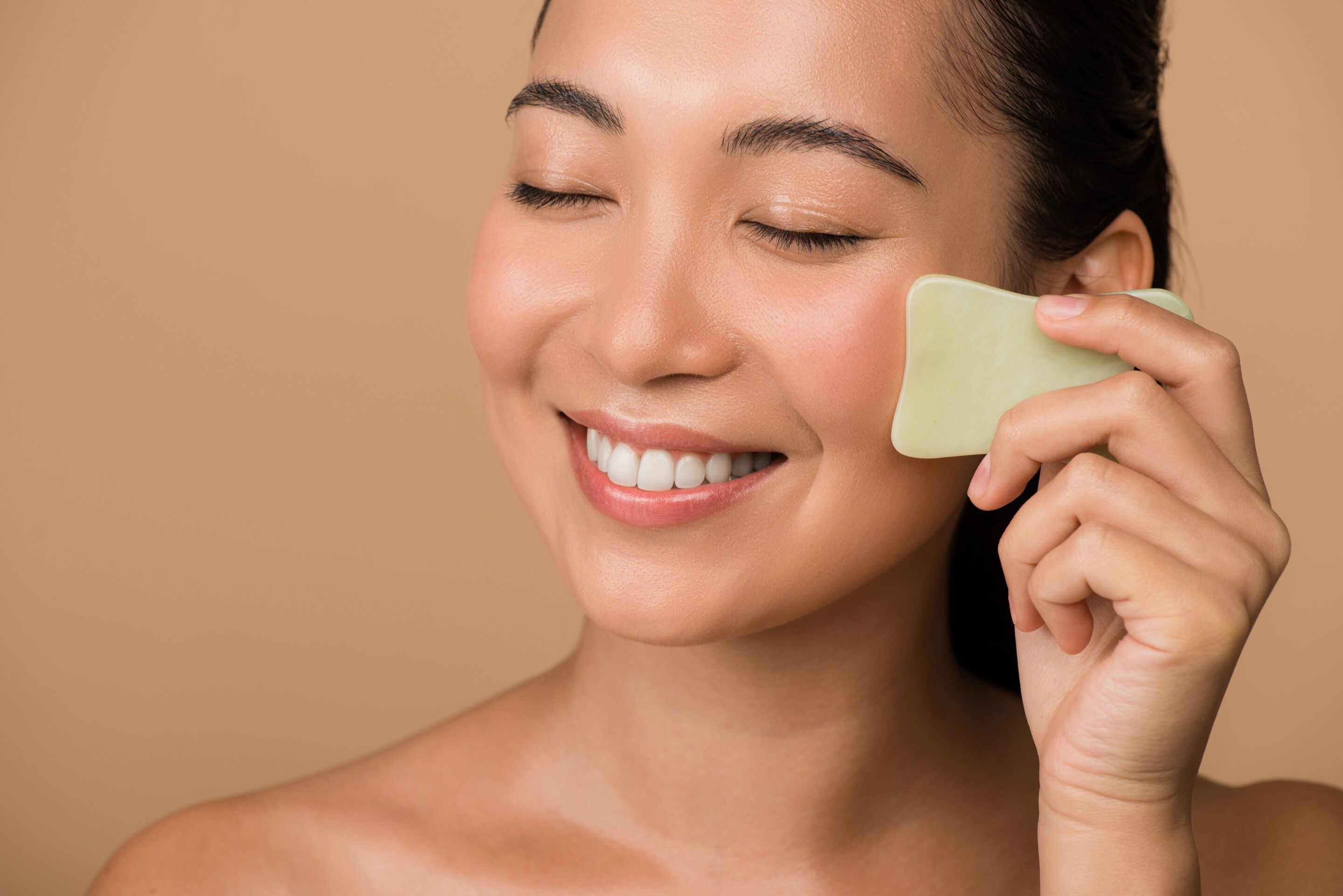 Girl with closed eyes using facial gua sha 