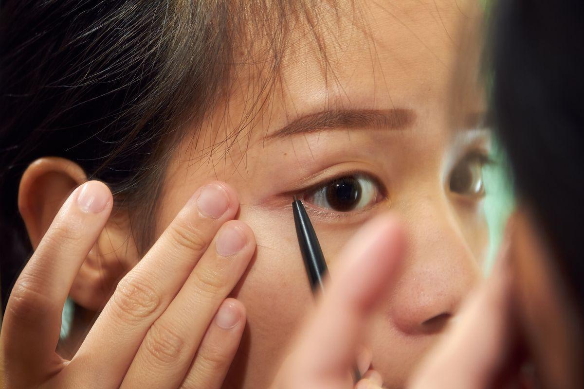 Asian girl applying eyeliner
