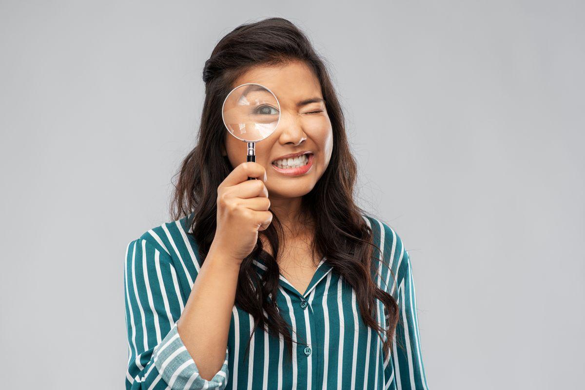 Asian woman looking through a magnifying glass
