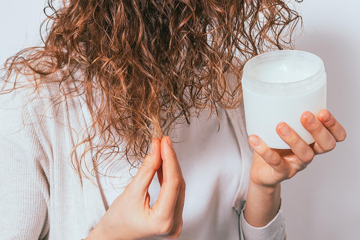 Woman applying coconut oil to curly hair