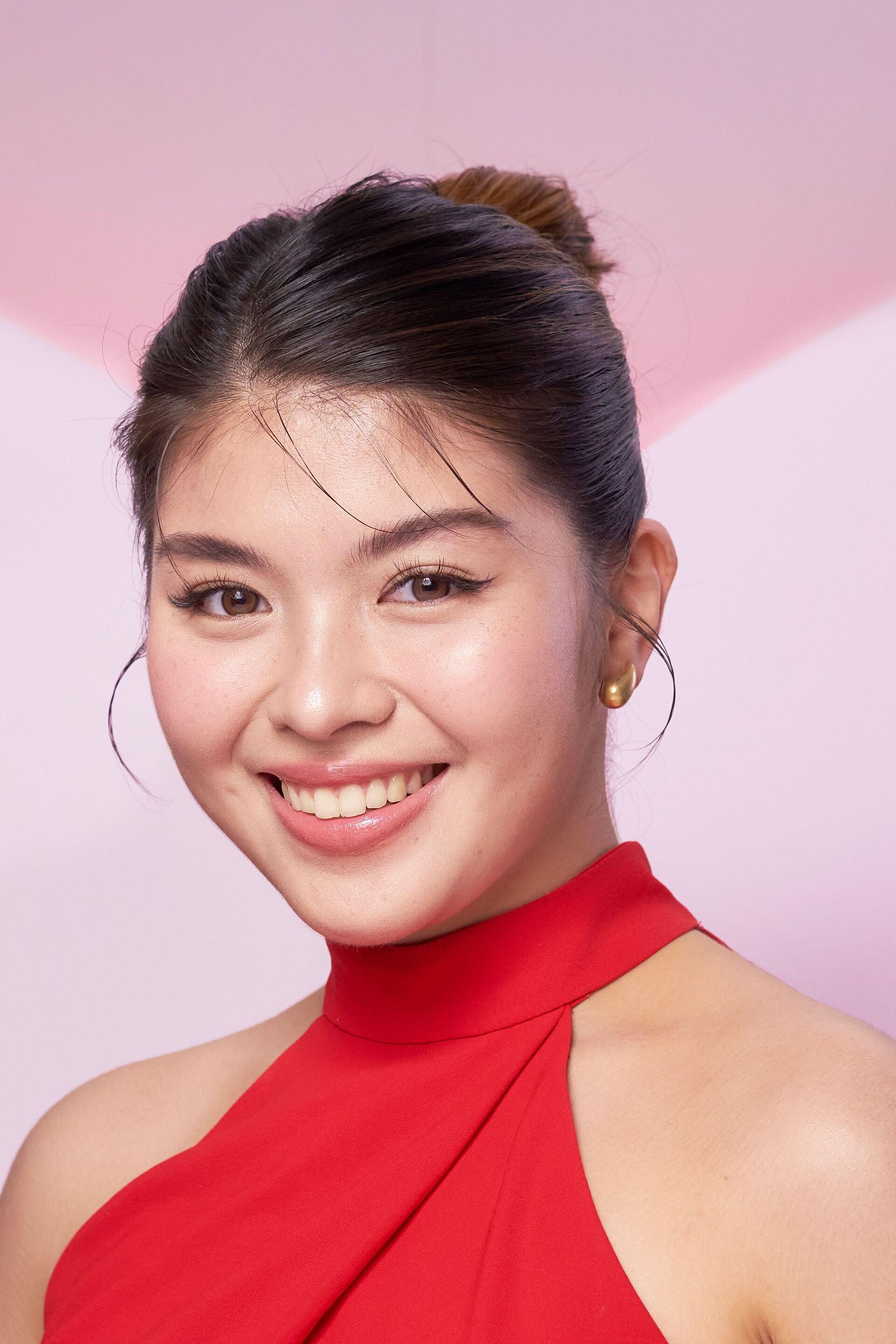 A portrait of an Asian woman in a red sleeveless top.