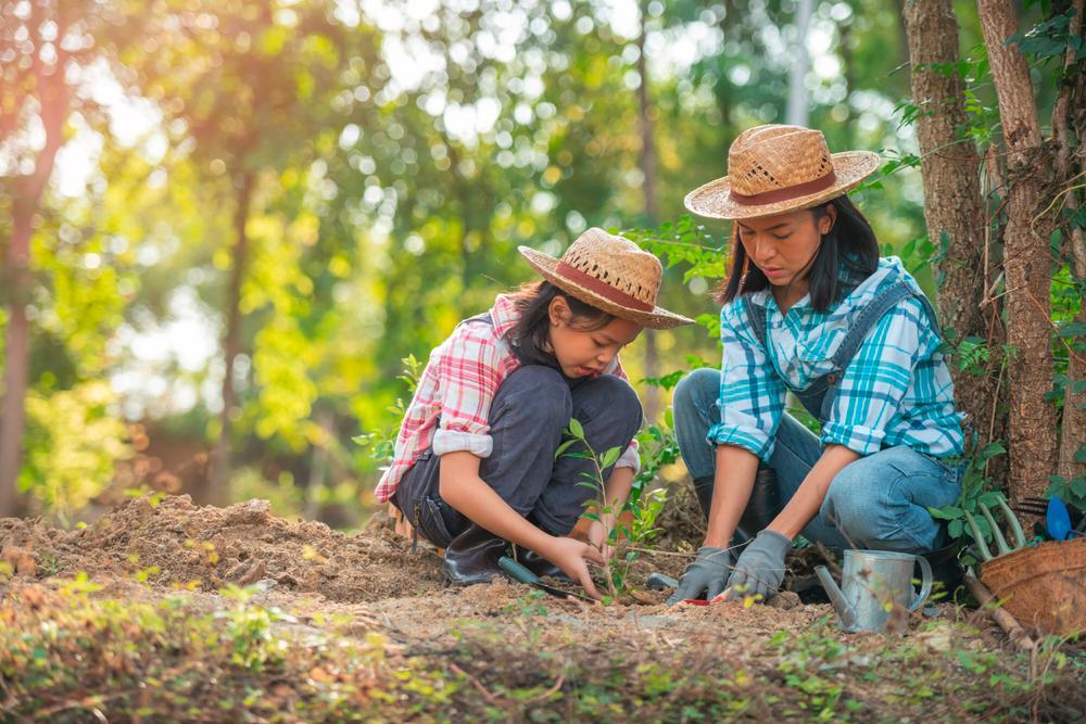 Asian woman and daughter gardening in hats.
