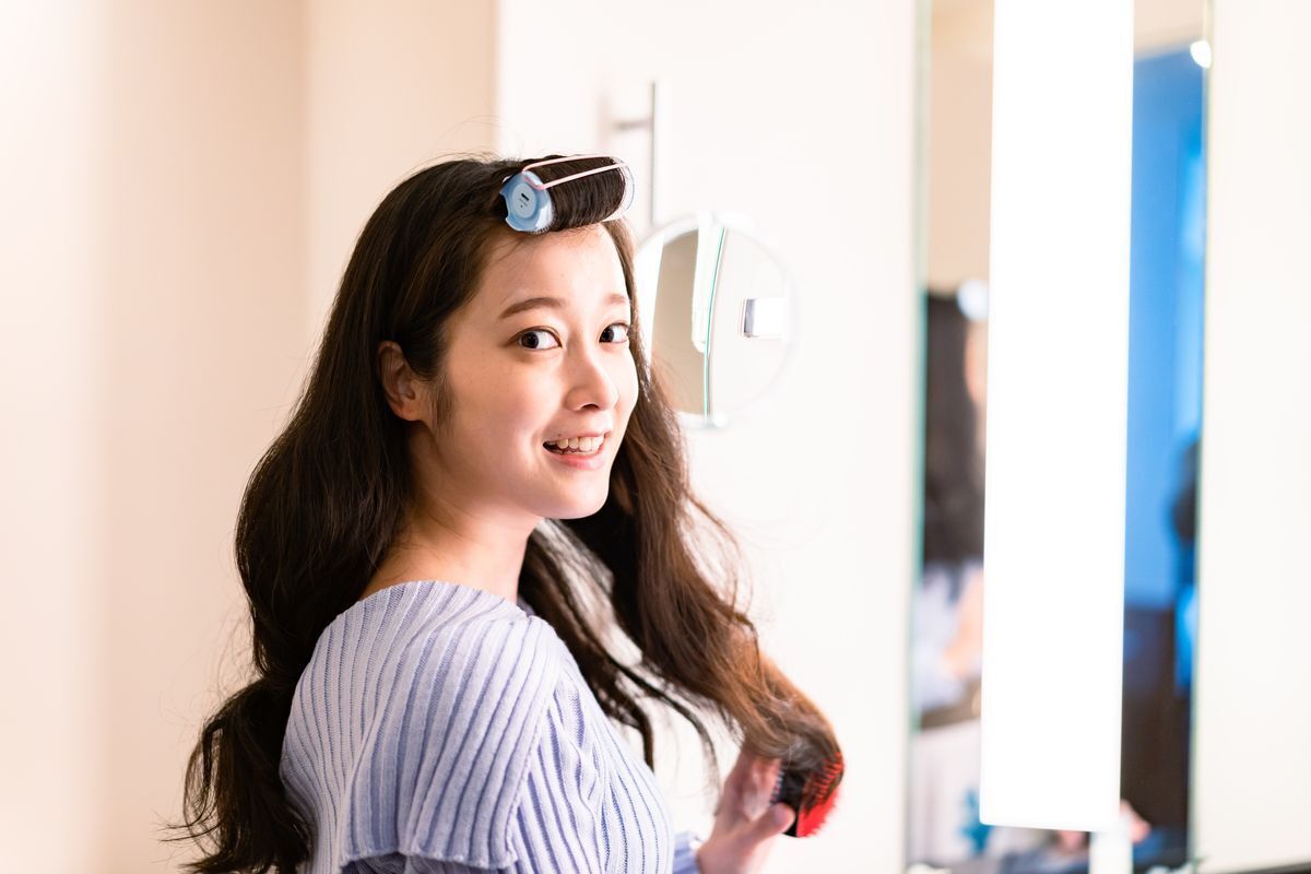 Woman styling her hair into soft waves with hair rollers.