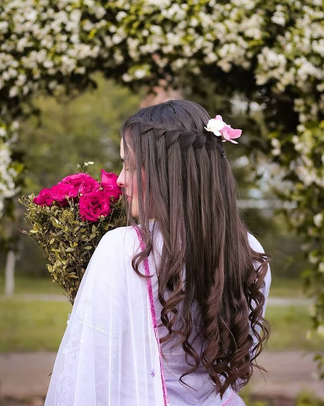 Woman with waterfall braid holding a bouquet.