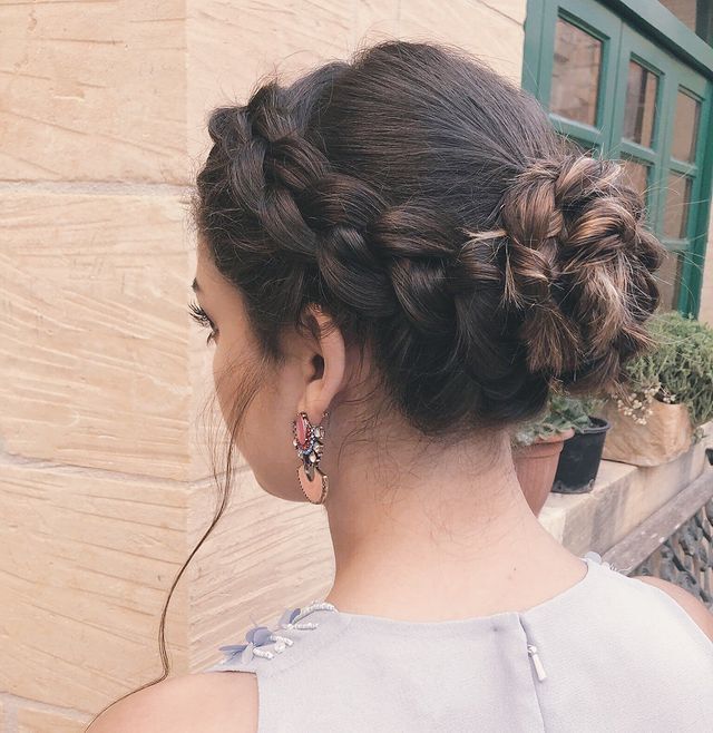 Woman with Dutch braid bun and accent earrings.