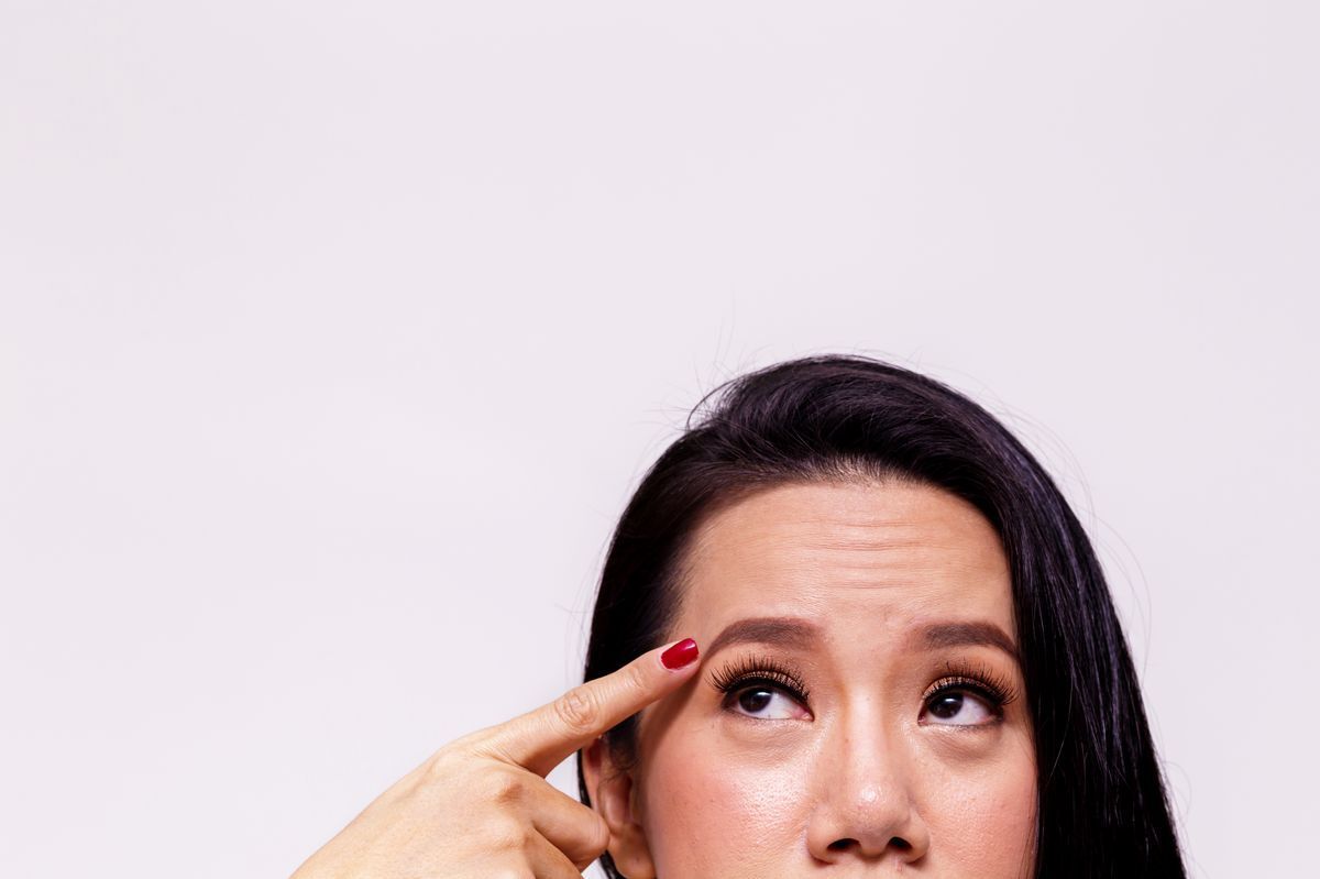 Asian woman pointing at fine lines on forehead