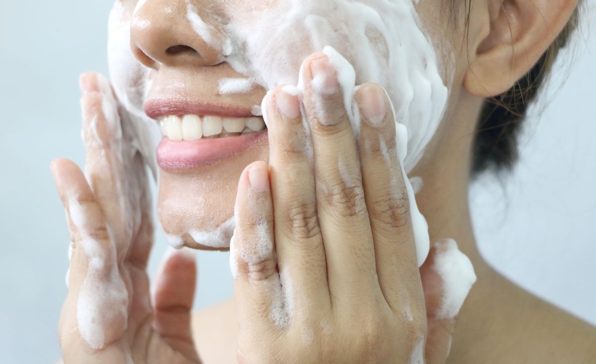 Asian woman cleansing her face with facial foam 