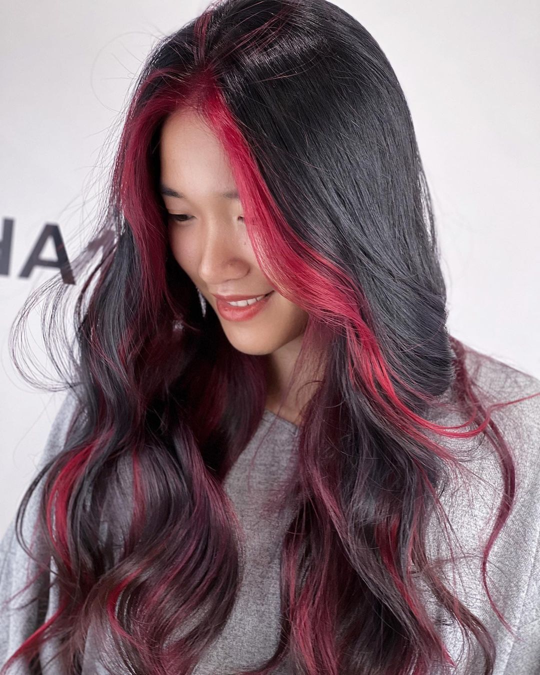 Woman posing with her red neon streaks and black hair.