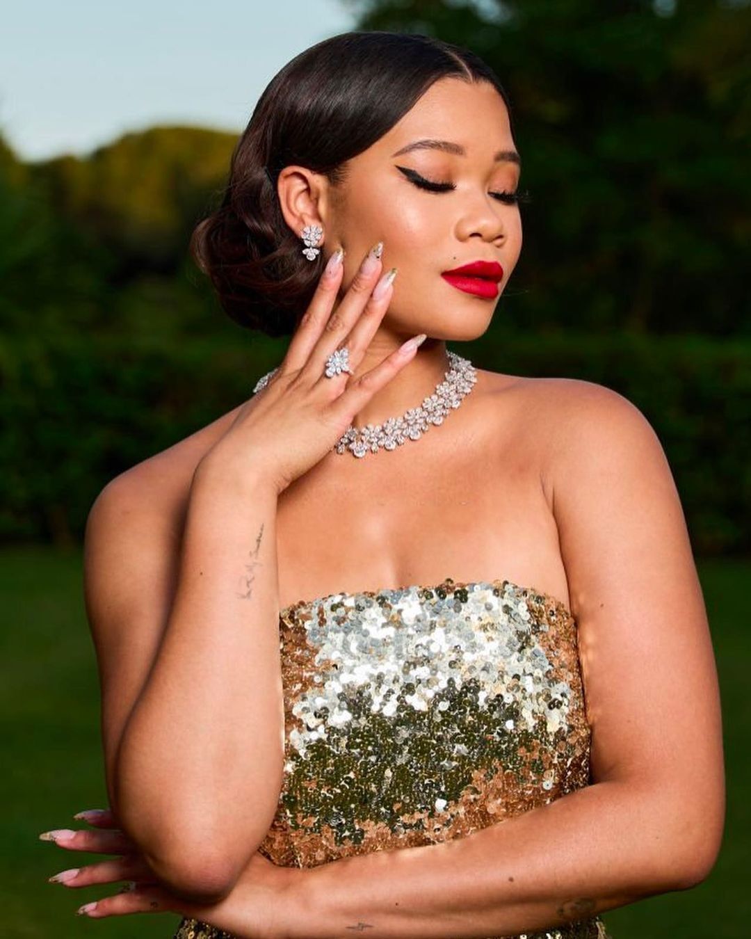 Storm Reid in sequin dress and faux bob hairdo posing with her hand on her jaw.