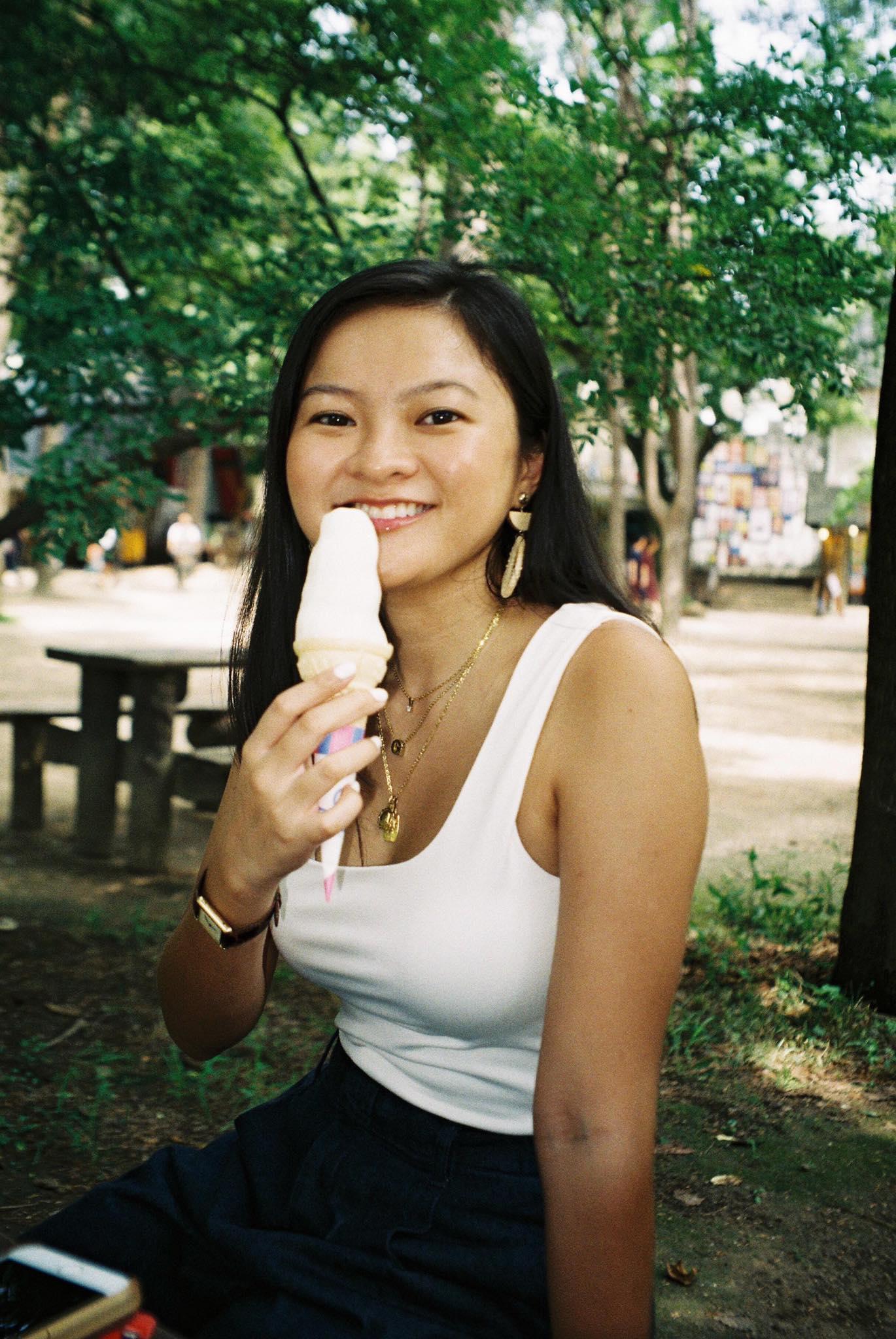 A woman in a white top holding an ice cream cone 