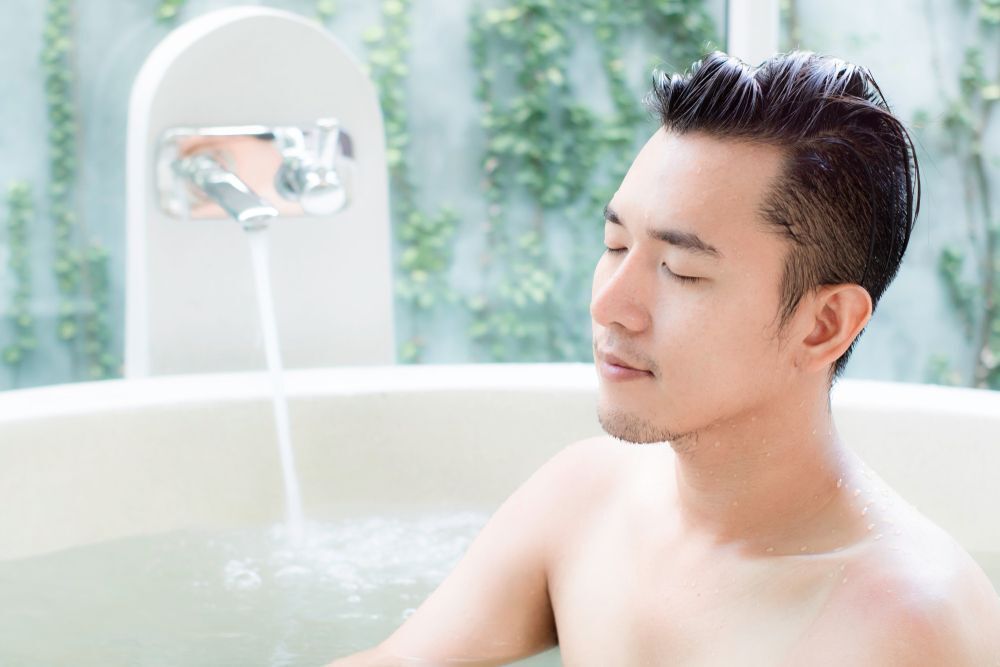 An Asian man closes his eyes as he is enjoying bath