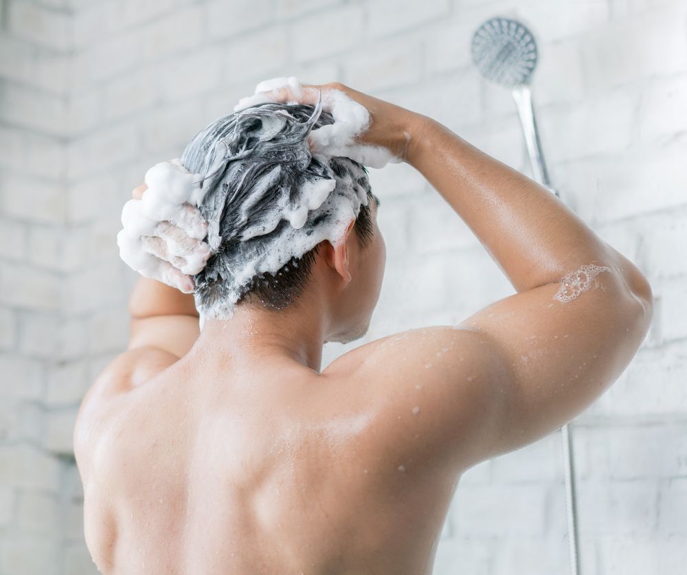 A man using shampoo while inside the shower