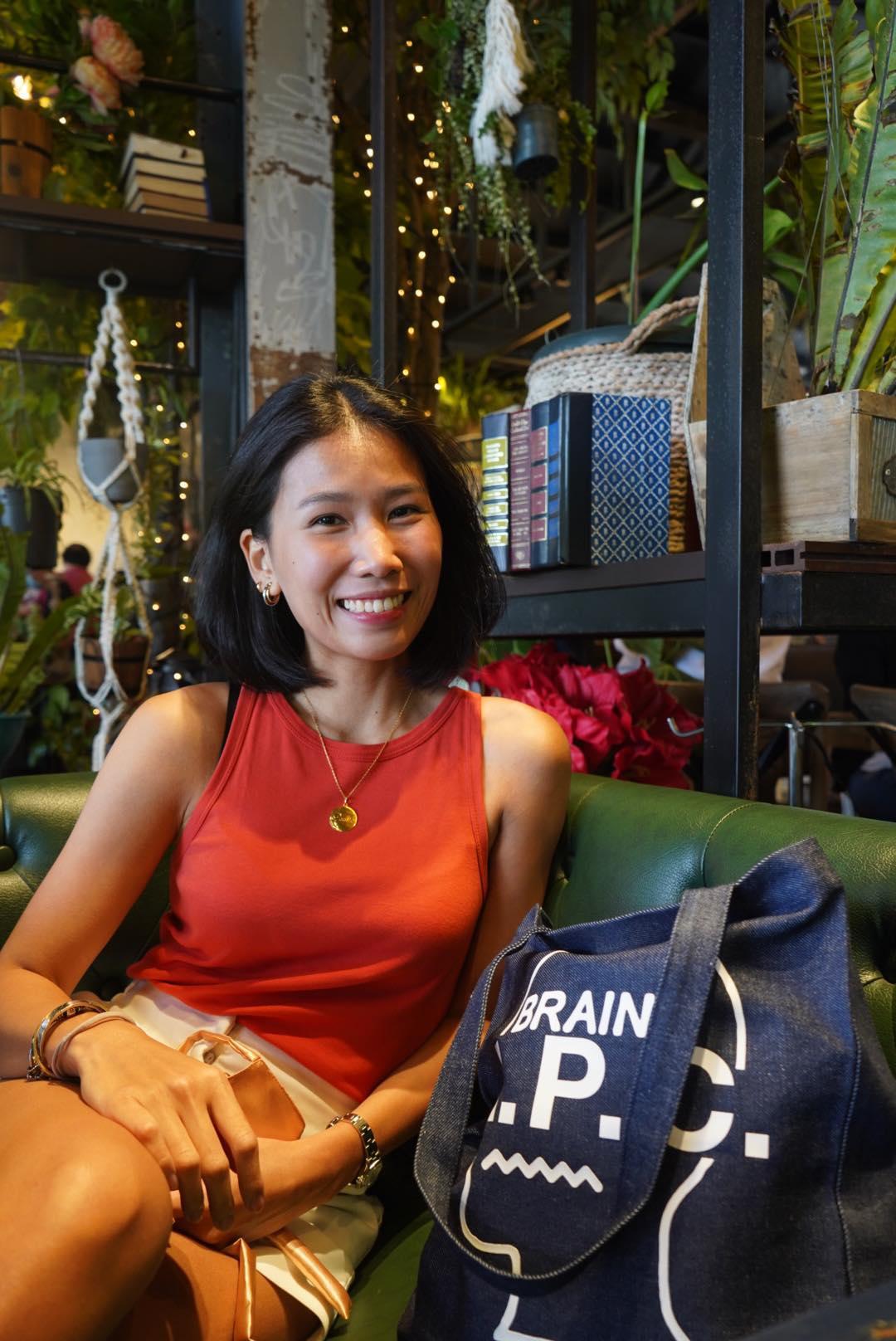 A woman in a red tank top sitting and smiling 